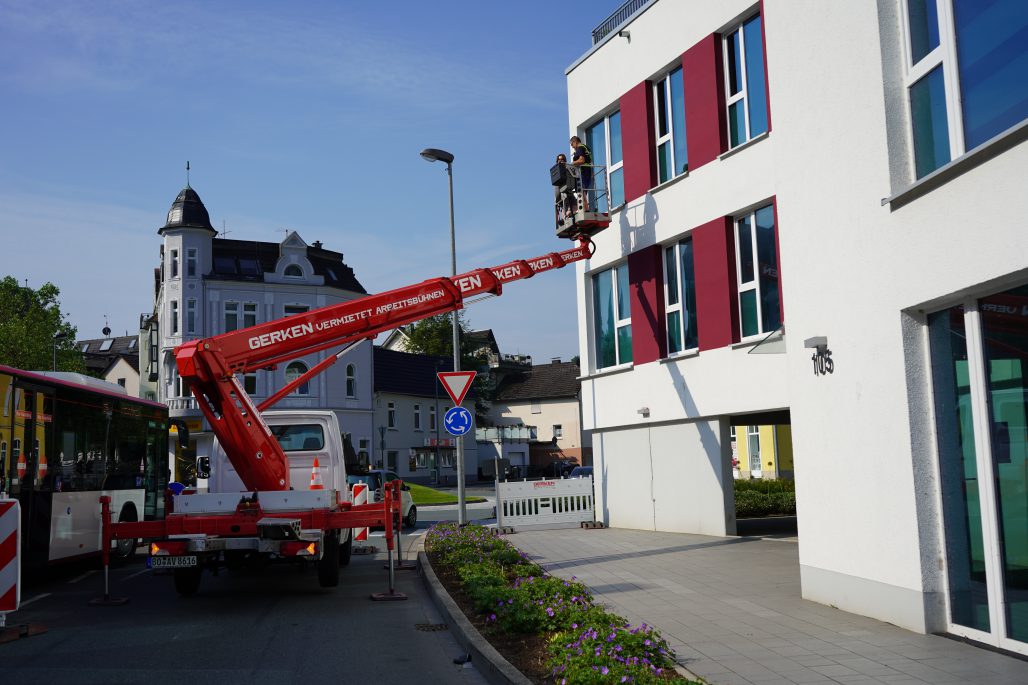 Ein Hubwagen befördert zwei Mitarbeiter der Weber Gruppe in Plettenberg an eine Fassade.