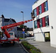 Ein Hubwagen befördert zwei Mitarbeiter der Weber Gruppe in Plettenberg an eine Fassade.