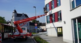 Ein Hubwagen befördert zwei Mitarbeiter der Weber Gruppe in Plettenberg an eine Fassade.