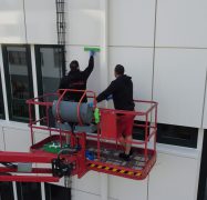 Zwei Glas- und Gebäudereiniger der Weber Gruppe im Einsatz. Auf einer Hubbühne bearbeiten sie eine Fassade am LANUV in Essen.