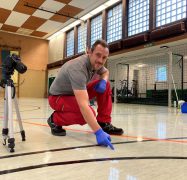 Gebäudereinigung in Hagen: Ein Mitarbeiter der Weber Gruppe kniet vor einem Harzfleck in einer Sporthalle in der Stadt Hagen.