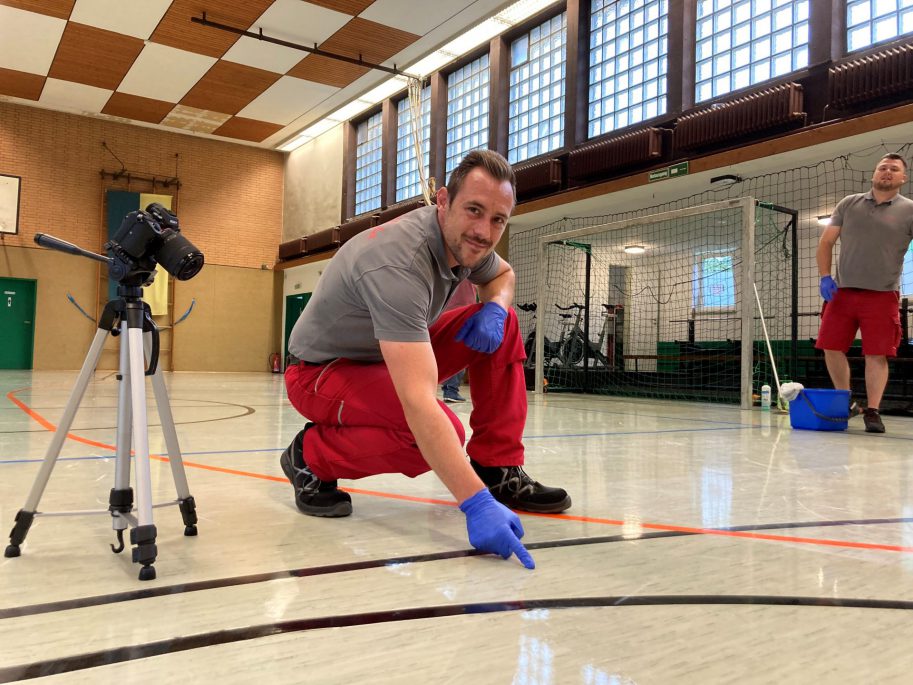 Gebäudereinigung in Hagen: Ein Mitarbeiter der Weber Gruppe kniet vor einem Harzfleck in einer Sporthalle in der Stadt Hagen.