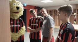 Bayer-04-Maskottchen Brian The Lion mit Glas- und Gebäudereinigern der Weber Gruppe sowie zwei Spielern von Bayer 04 Leverkusen.