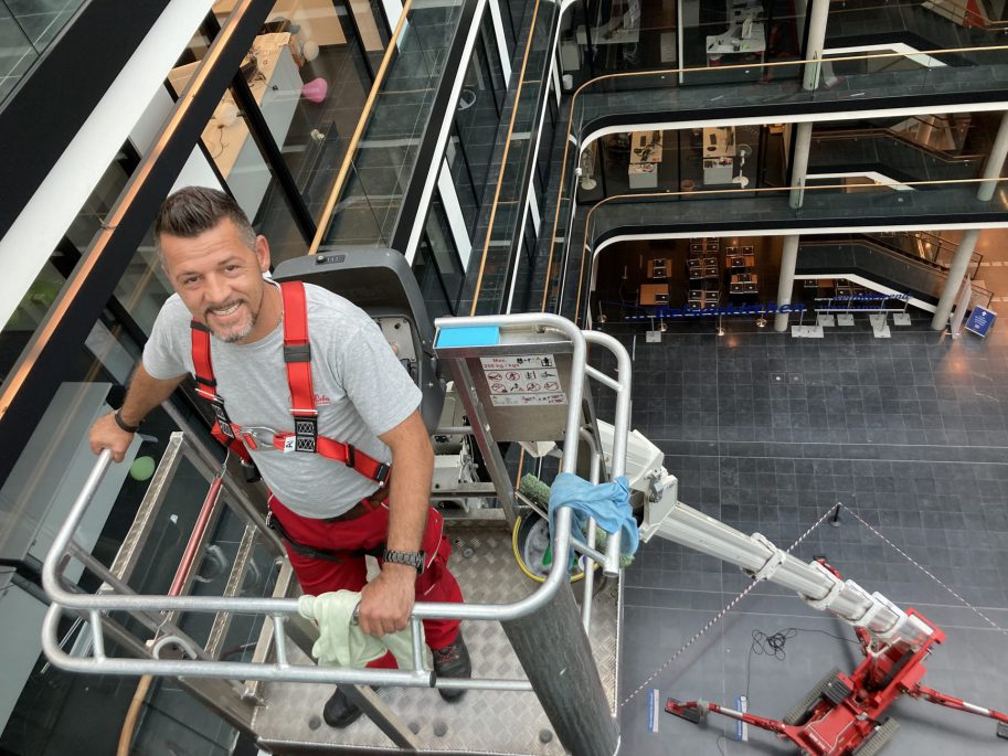 Ein Glas- und Gebäudereiniger der Weber Gruppe reinigt die Glasgeländer im Hans-Sachs-Haus in Gelsenkirchen.