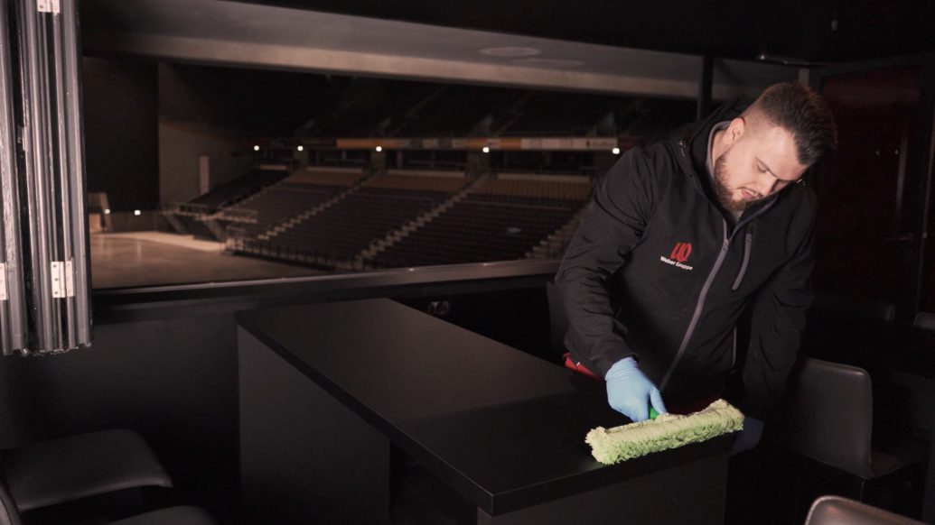 Gebäudereinigung in Oberhausen: Ein Mitarbeiter von Rudolf Weber trägt die Langzeitdesinfektion auf einen Tisch in der Rudolf Weber-ARENA in Oberhausen auf.