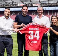 Stephan Rathgeber, Florian Dederichs, Andreas Weber und Lara Friese halten ein Trikot mit der Nummer 34 und dem Namen "Rudolf Weber" in die Kamera.