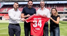 Stephan Rathgeber, Florian Dederichs, Andreas Weber und Lara Friese halten ein Trikot mit der Nummer 34 und dem Namen "Rudolf Weber" in die Kamera.